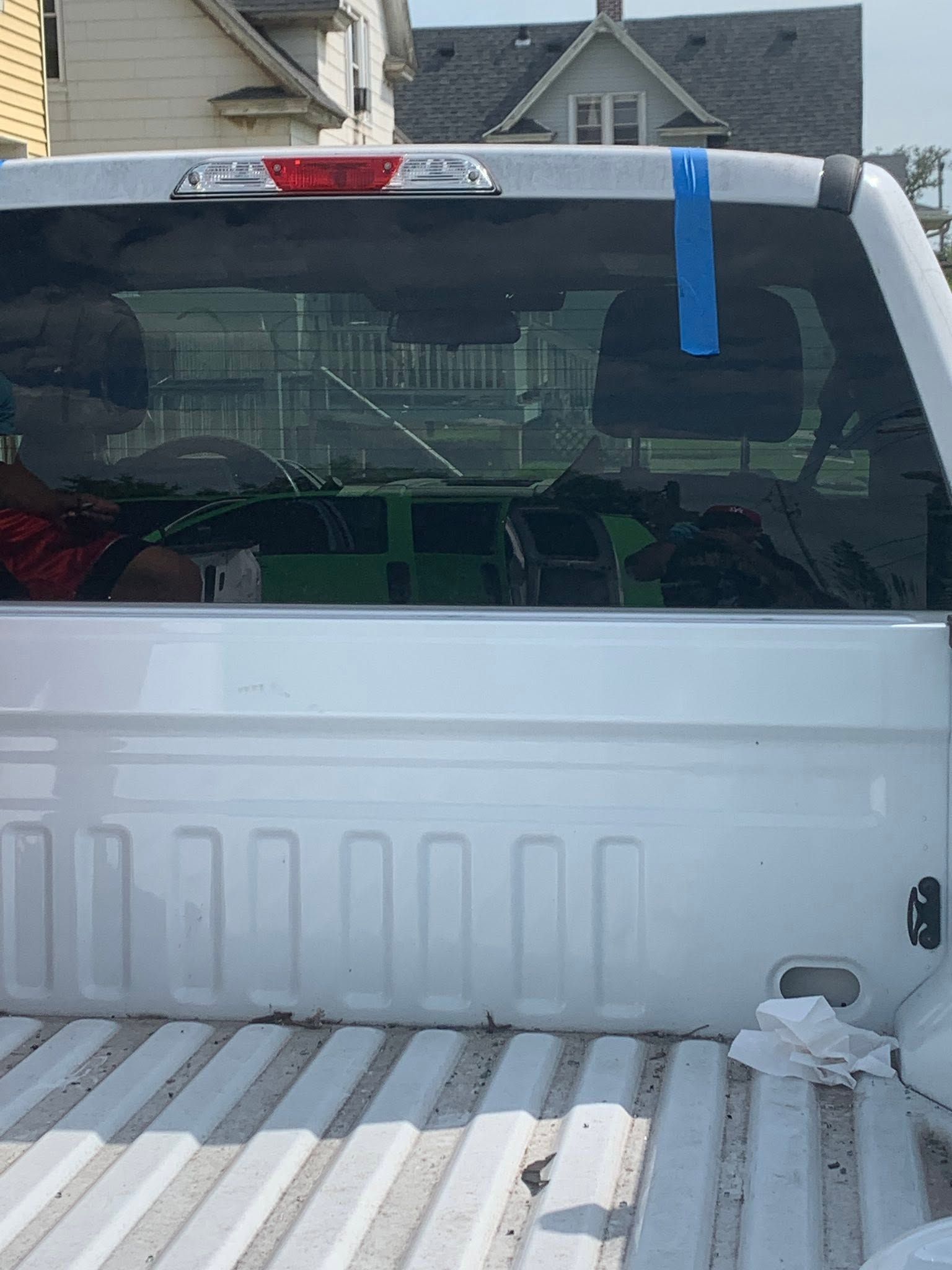 White pickup truck bed with striped floor, viewed from behind in a residential driveway.