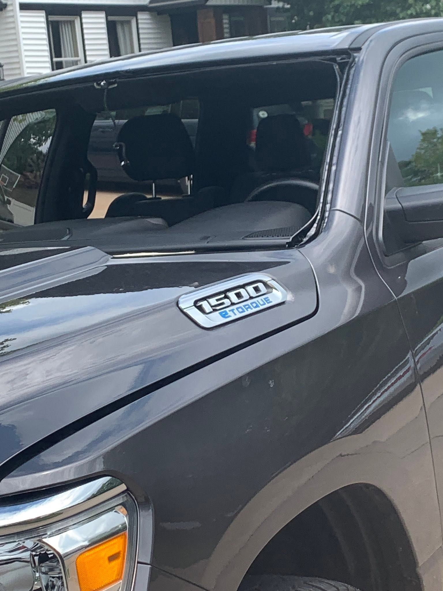 Black truck’s front corner with a broken windshield and a hood badge visible.
