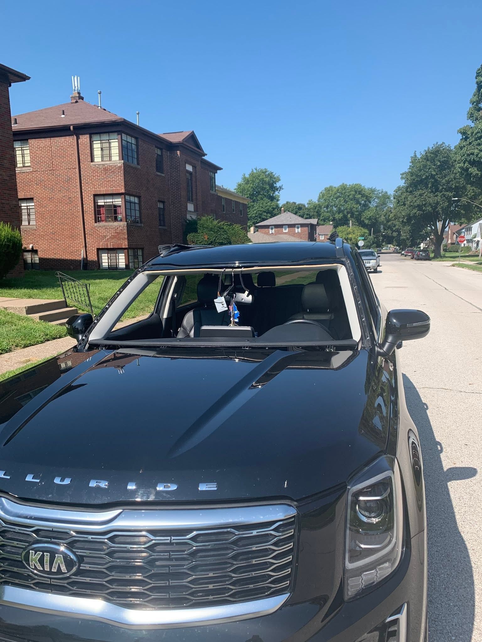 Black Jeep SUV parked on a sunny residential street, with a cracked windshield.