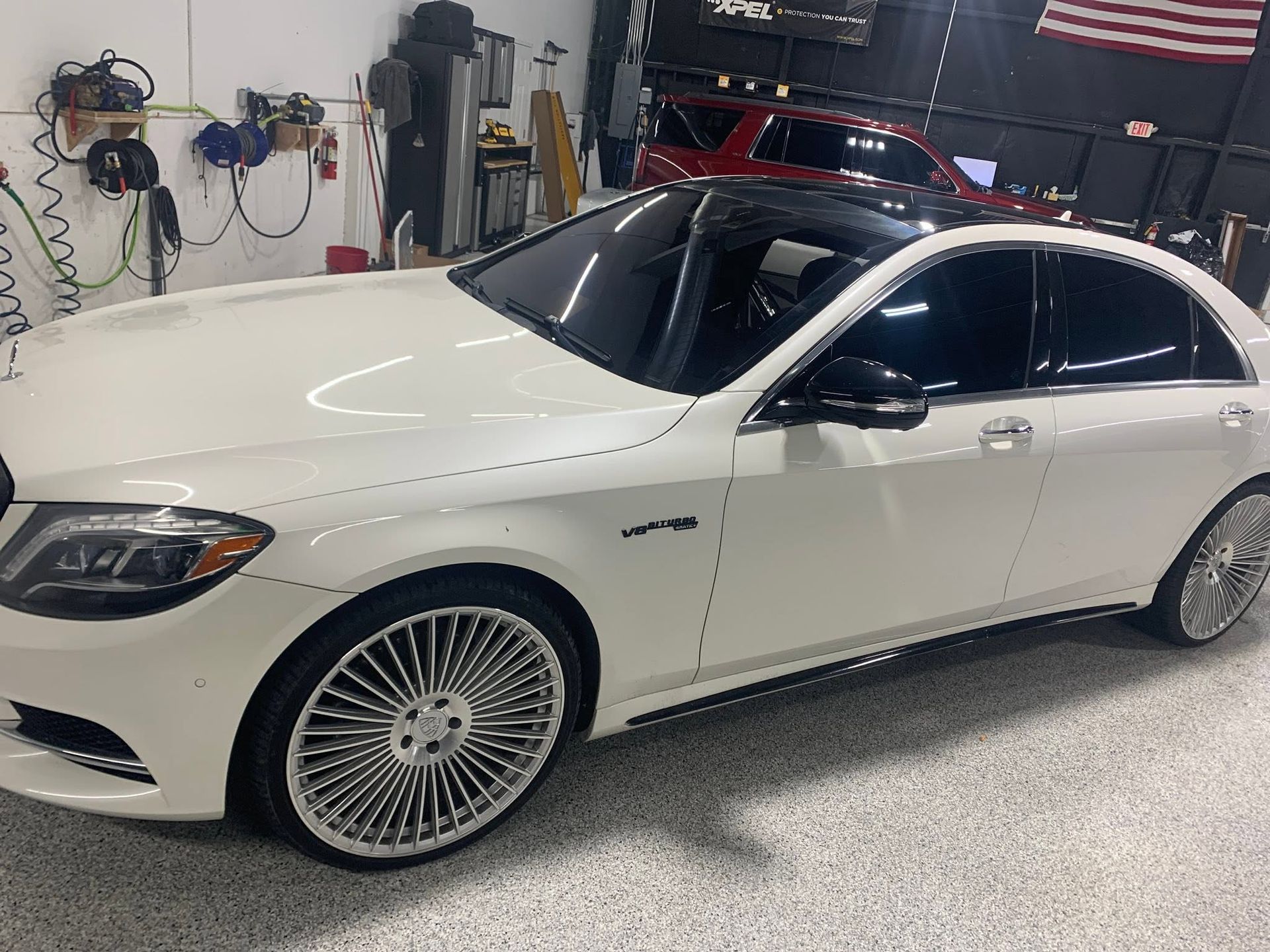 White luxury sedan in a garage, with tinted windows and custom rims.
