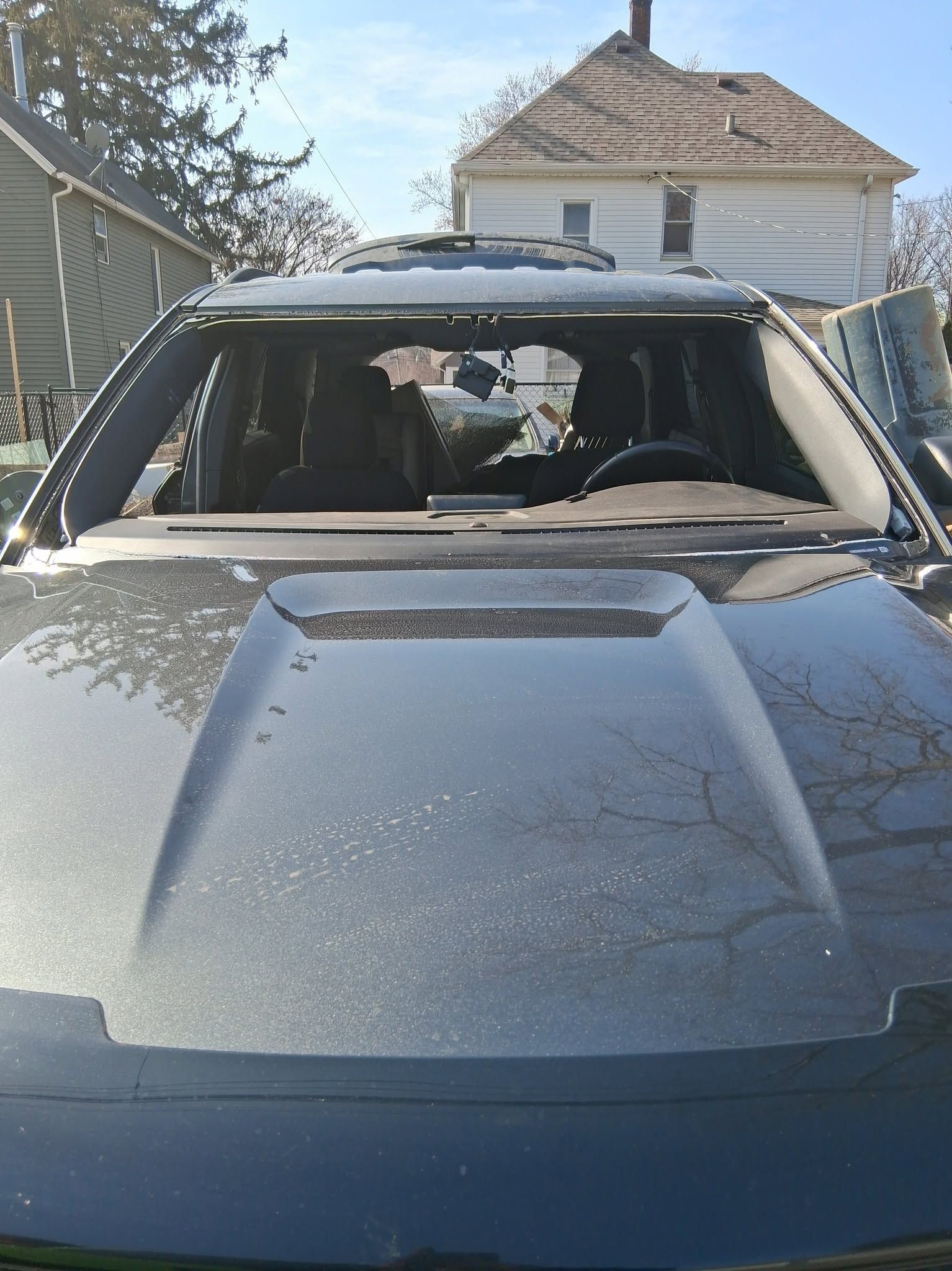 Gray SUV parked in a driveway, viewed from the front with a house in the background.