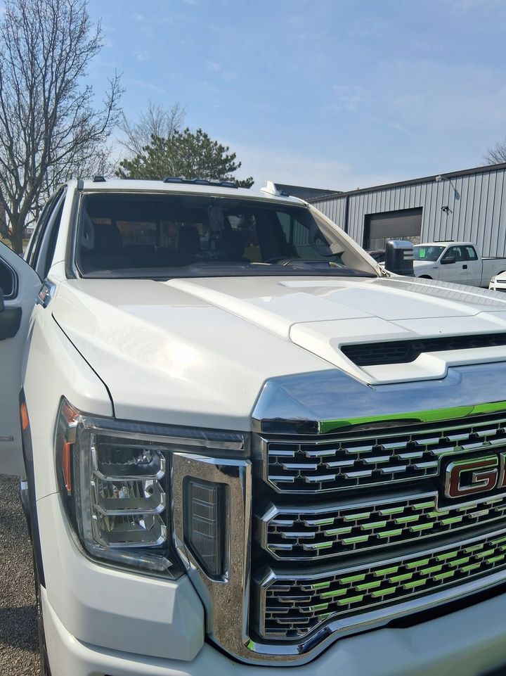 White GMC pickup truck parked outdoors in front of a building on a sunny day