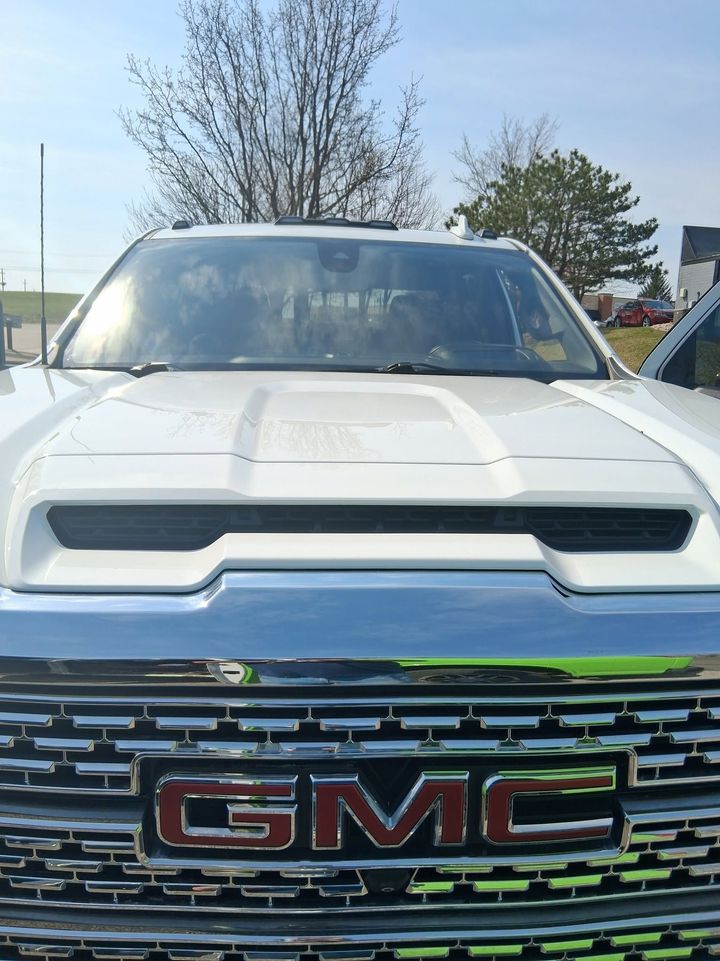 Front view of a white GMC truck with a chrome grille parked outdoors under a blue sky