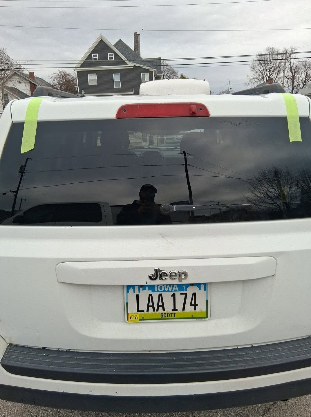 Rear view of a white Jeep with neon tape on the back window and a New York license plate.