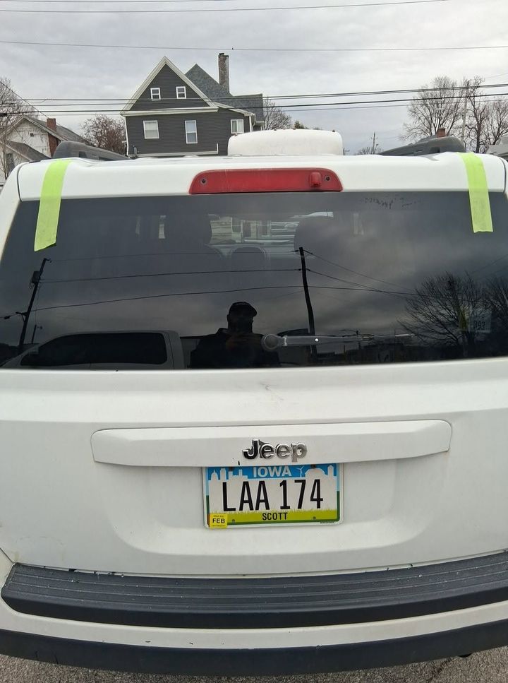 Rear of a white Jeep with a yellow New Jersey plate, parked on a snowy street.