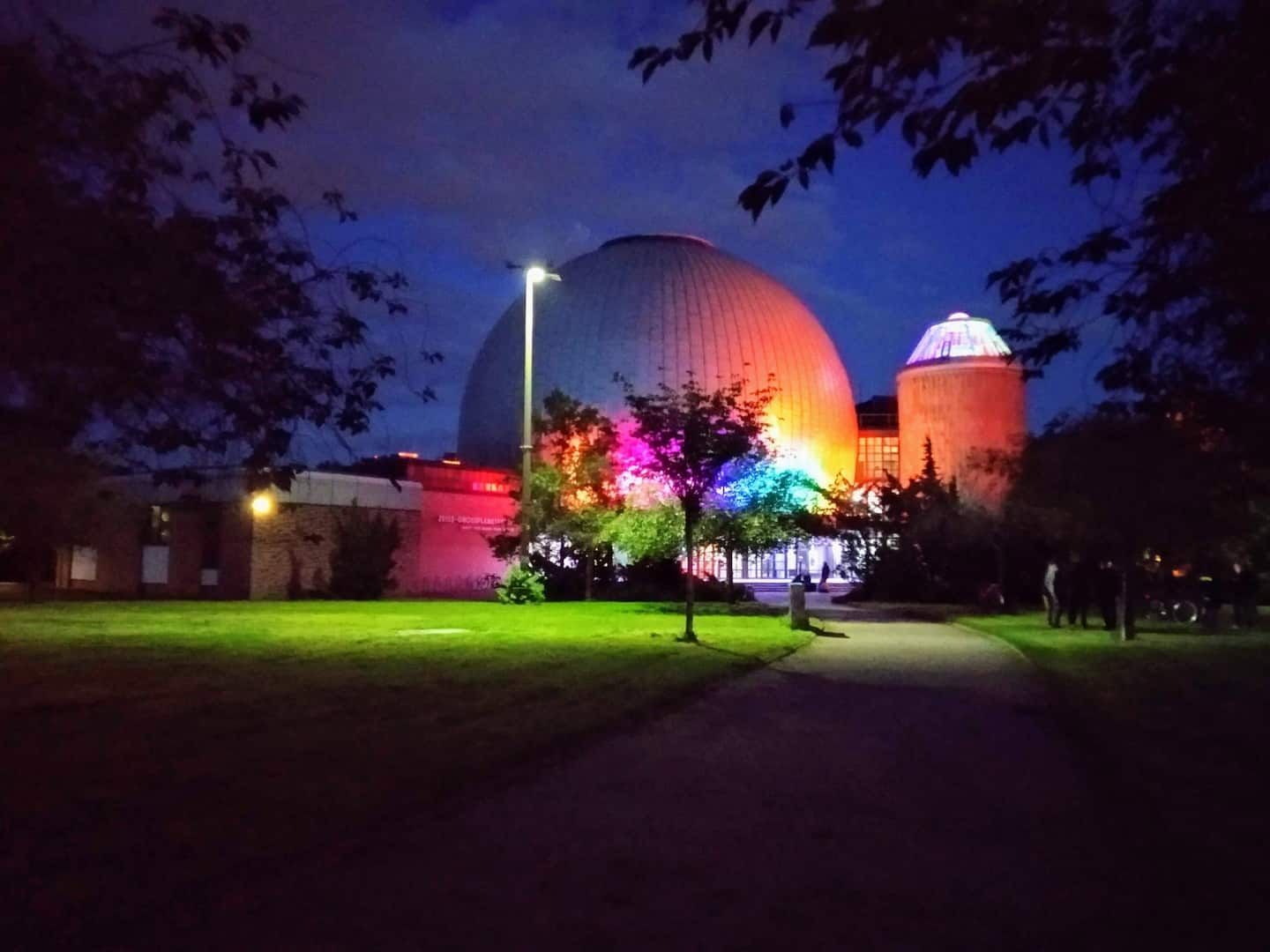A large dome of the planetarium in Berlin Prenzlauer Berg is lit up at night in a park