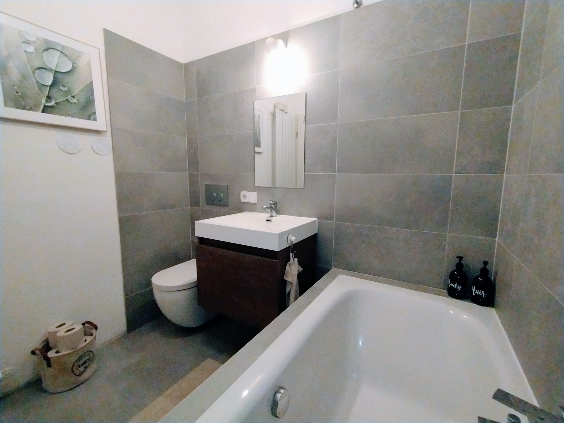 A bathroom of our holiday apartment in Berlin with a bathtub , sink , toilet and mirror.