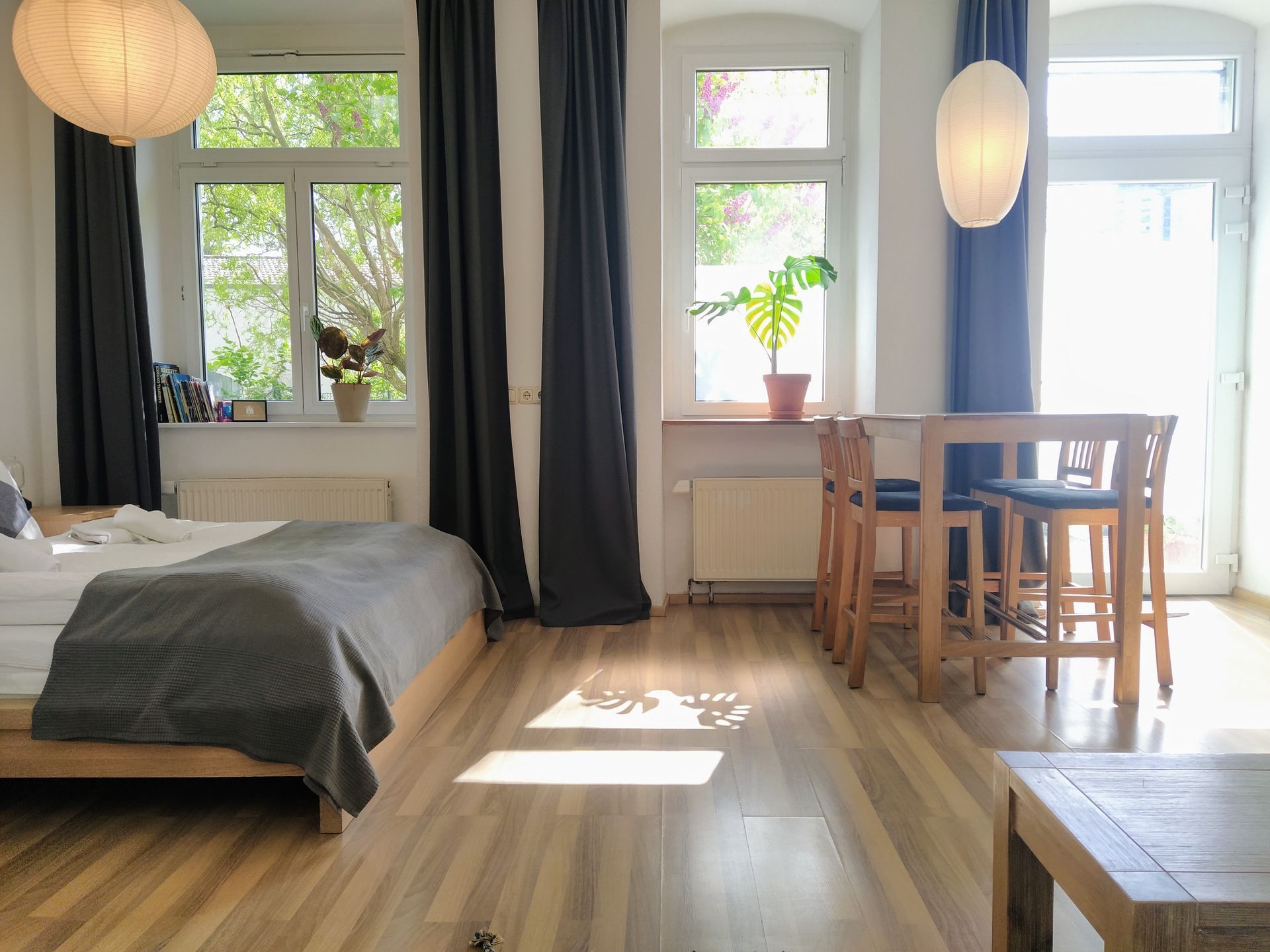 A bedroom in holiday rental in Berlin with a bed , table , chairs and curtains.