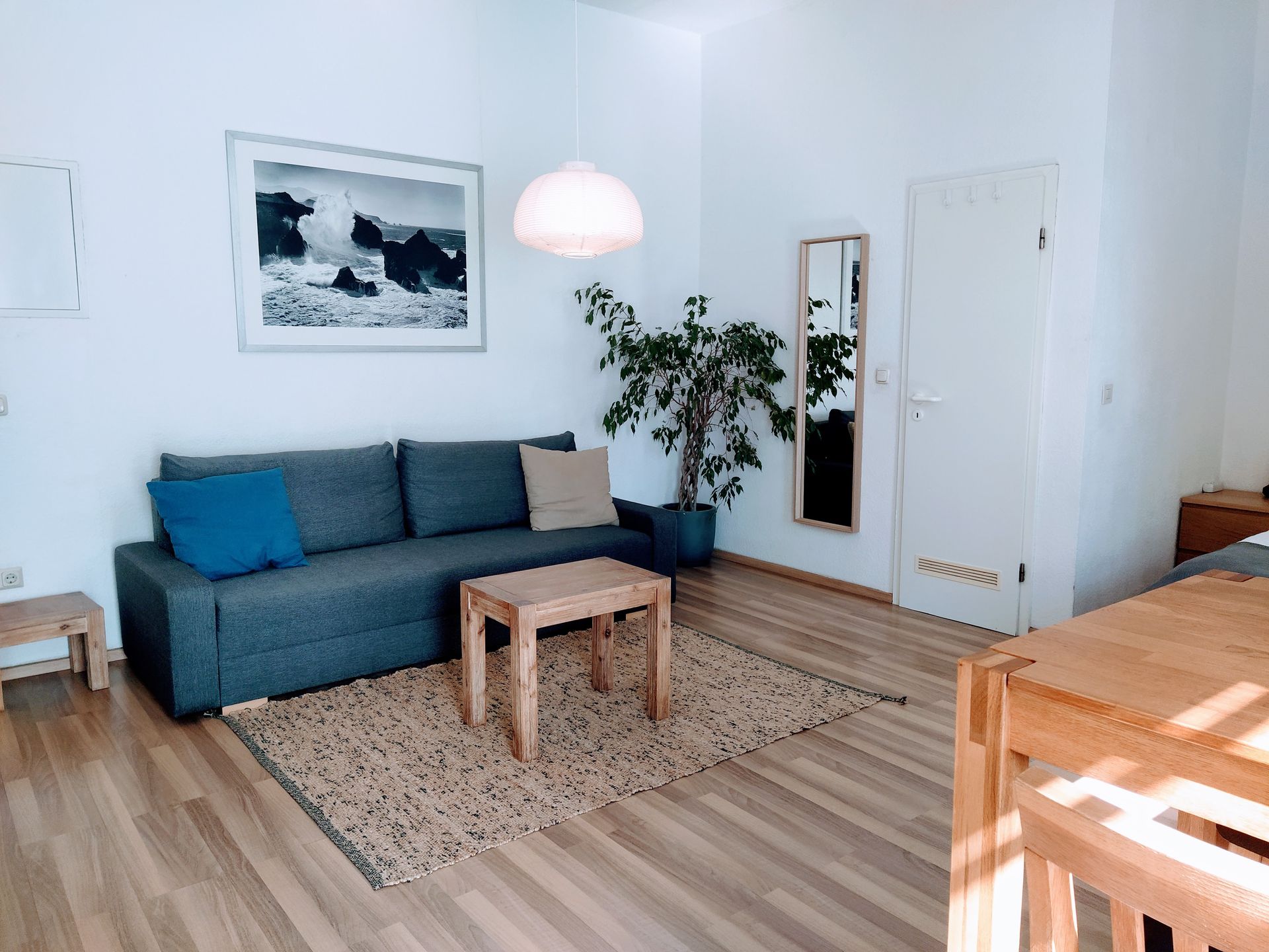 A living room in holiday rental in Berlin with a couch , table , and mirror.