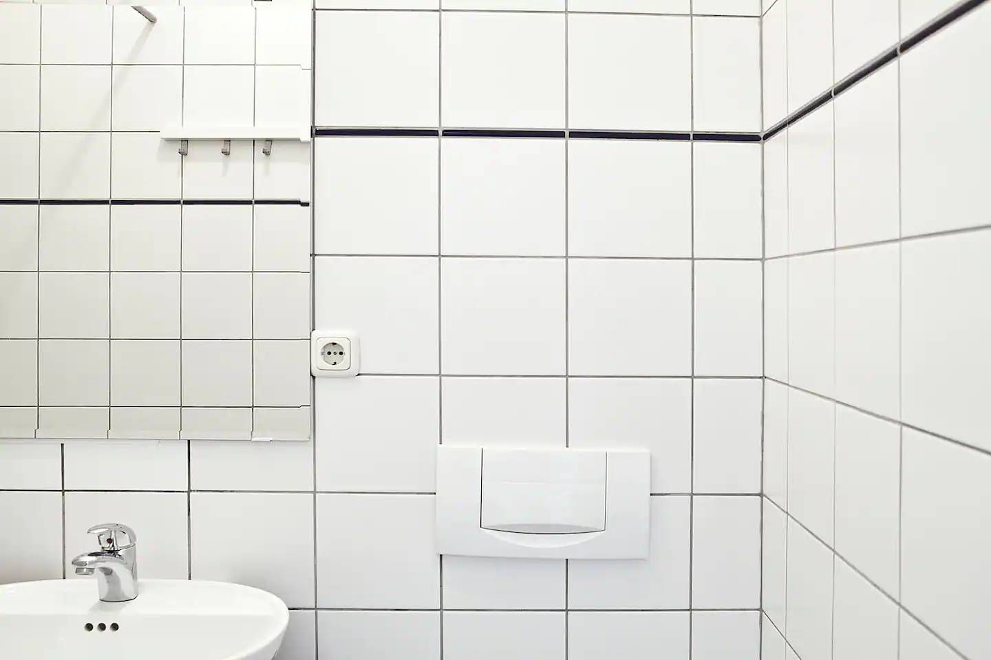 A bathroom with white tiles and a sink and mirror in our holiday apartment in Berlin
