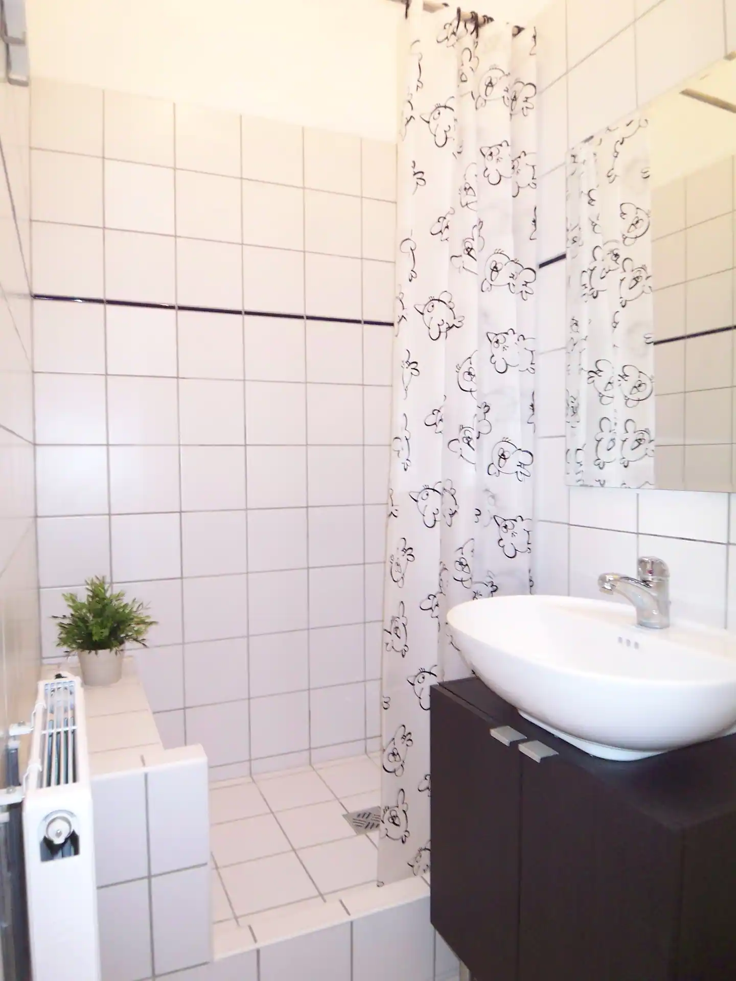A bathroom with a sink and a shower curtain in our holiday apartment in Berlin