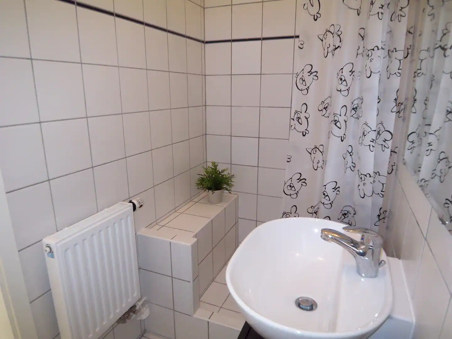 A bathroom with a sink and a shower curtain in our holiday apartment in Berlin