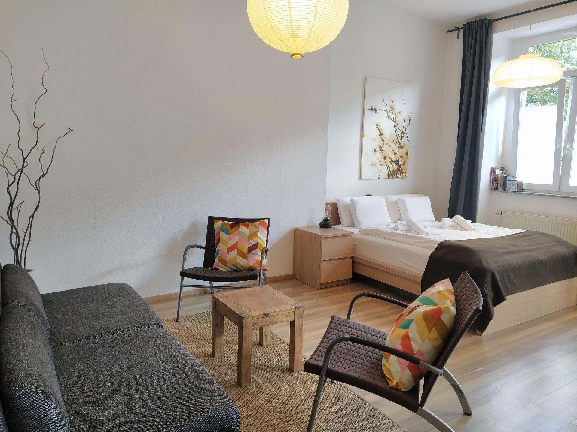 Das Wohnzimmer unserer Ferienwohnung im Prenzlauer Berg mit Couch, Sessel, Tisch und Bett.