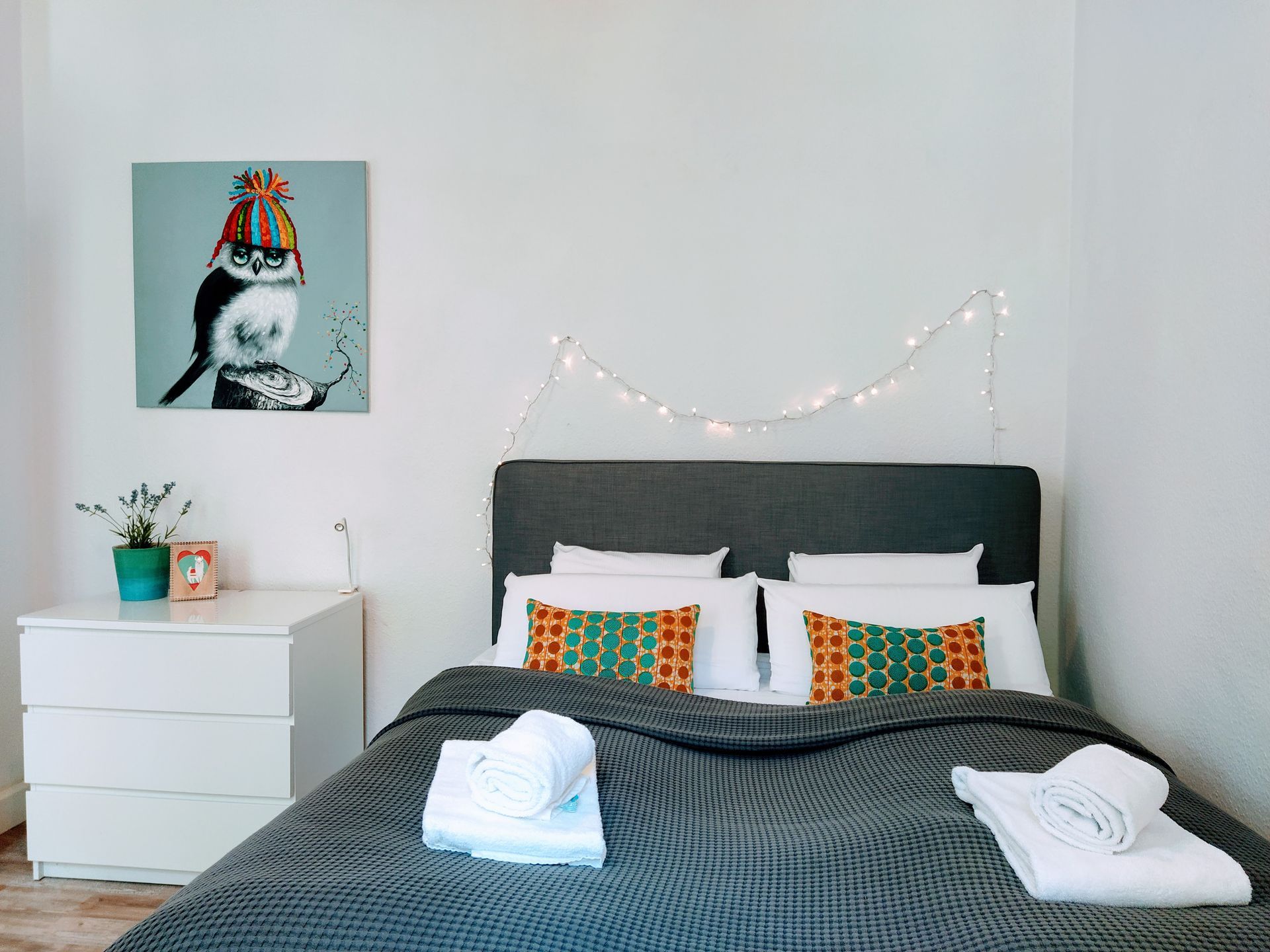 A bedroom with a bed , nightstand , and a painting on the wall in our holiday apartment in Berlin.