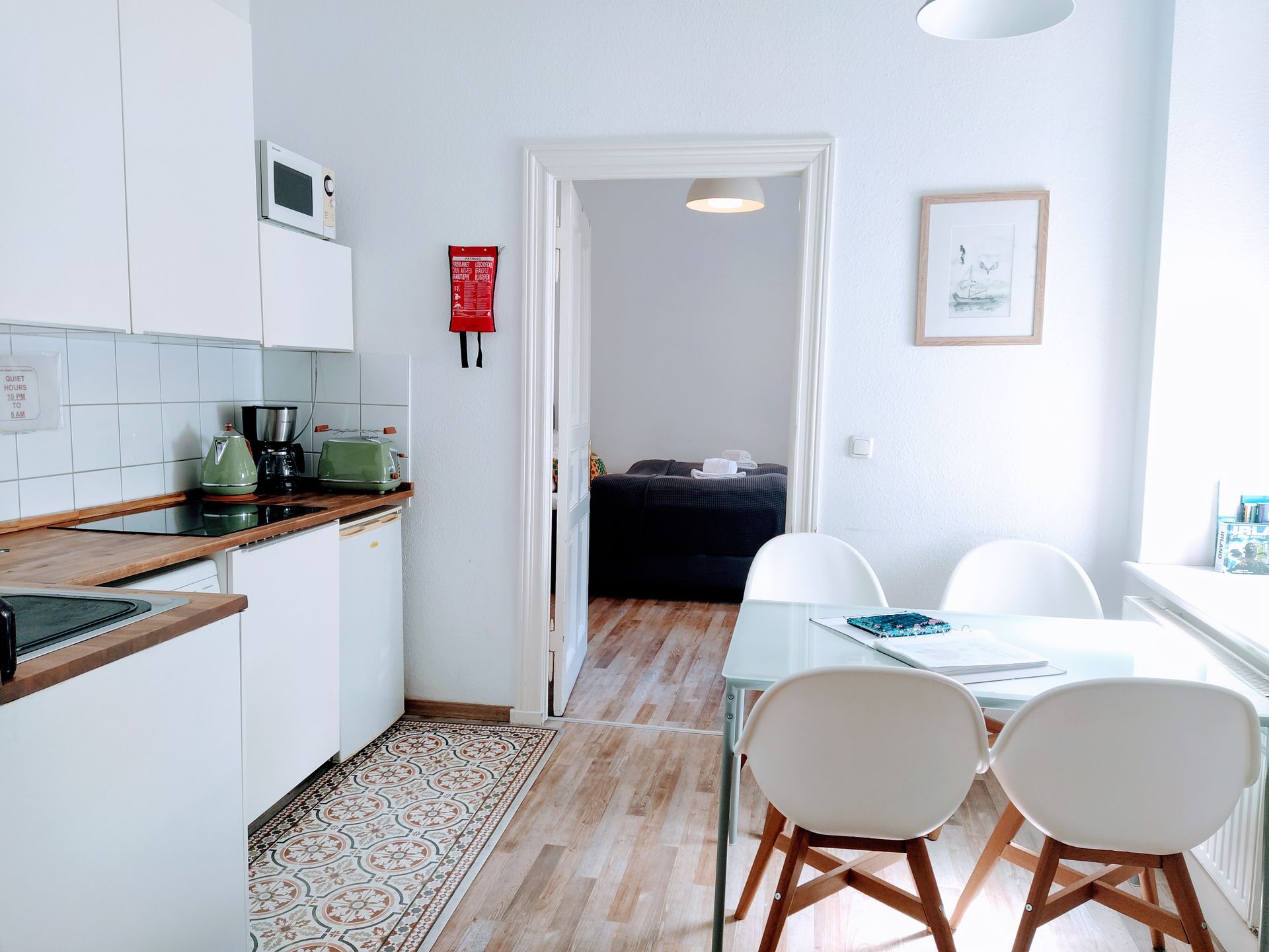 A kitchen with a table and chairs and a fire blanket on the wall.