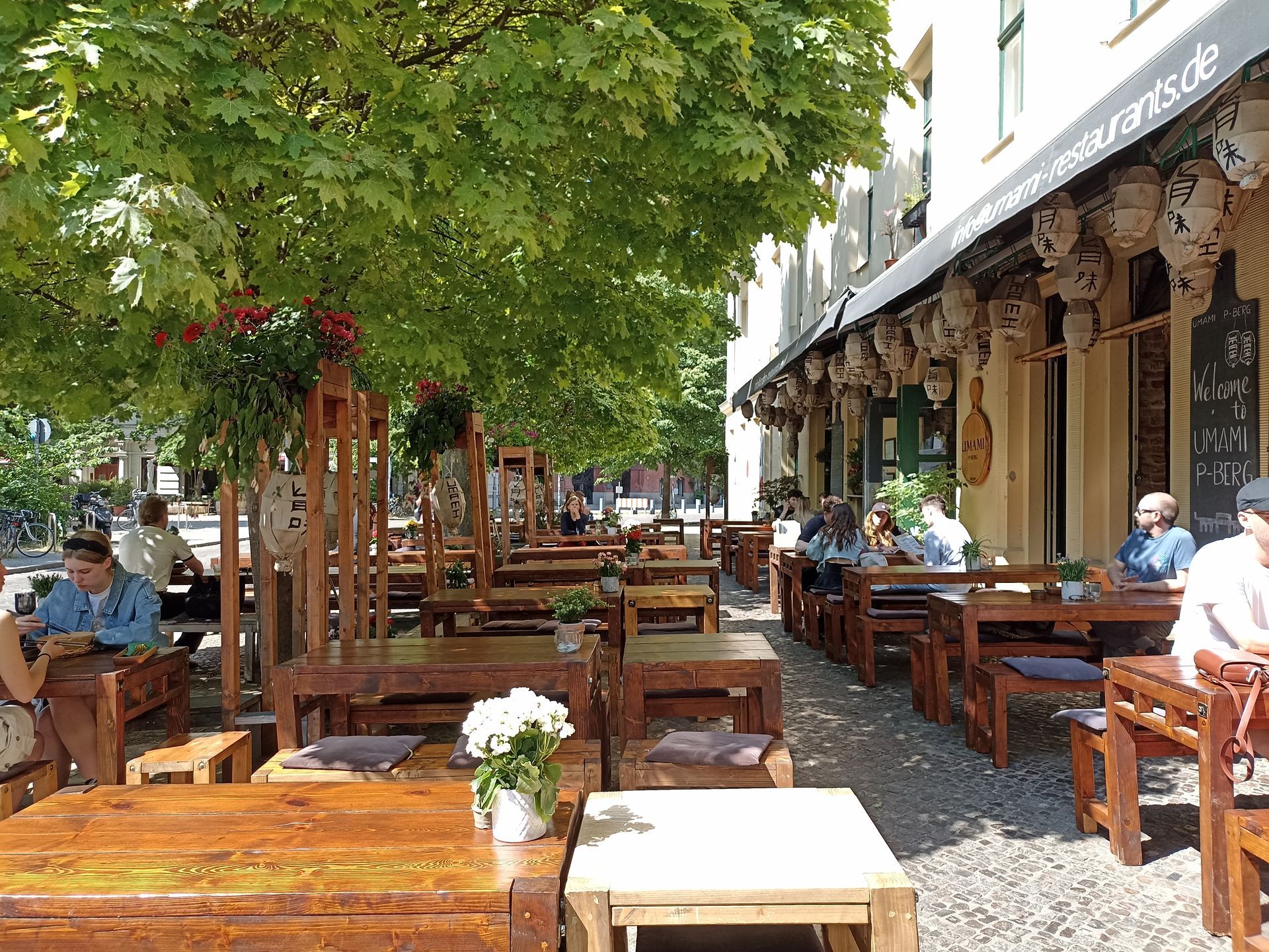A group of people are sitting at tables outside of the umami restaurant.