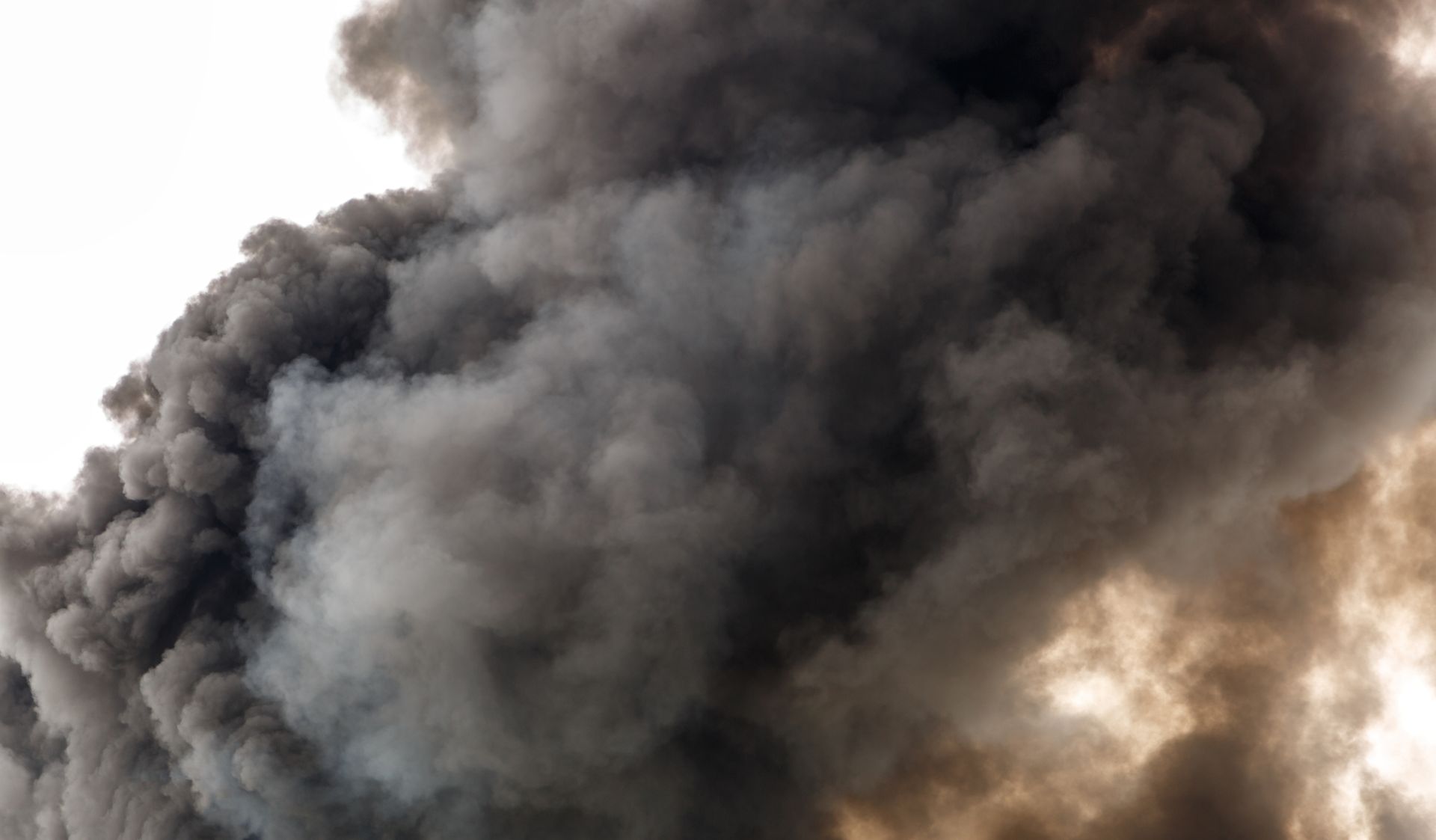 A large cloud of black smoke is coming out of a fire.