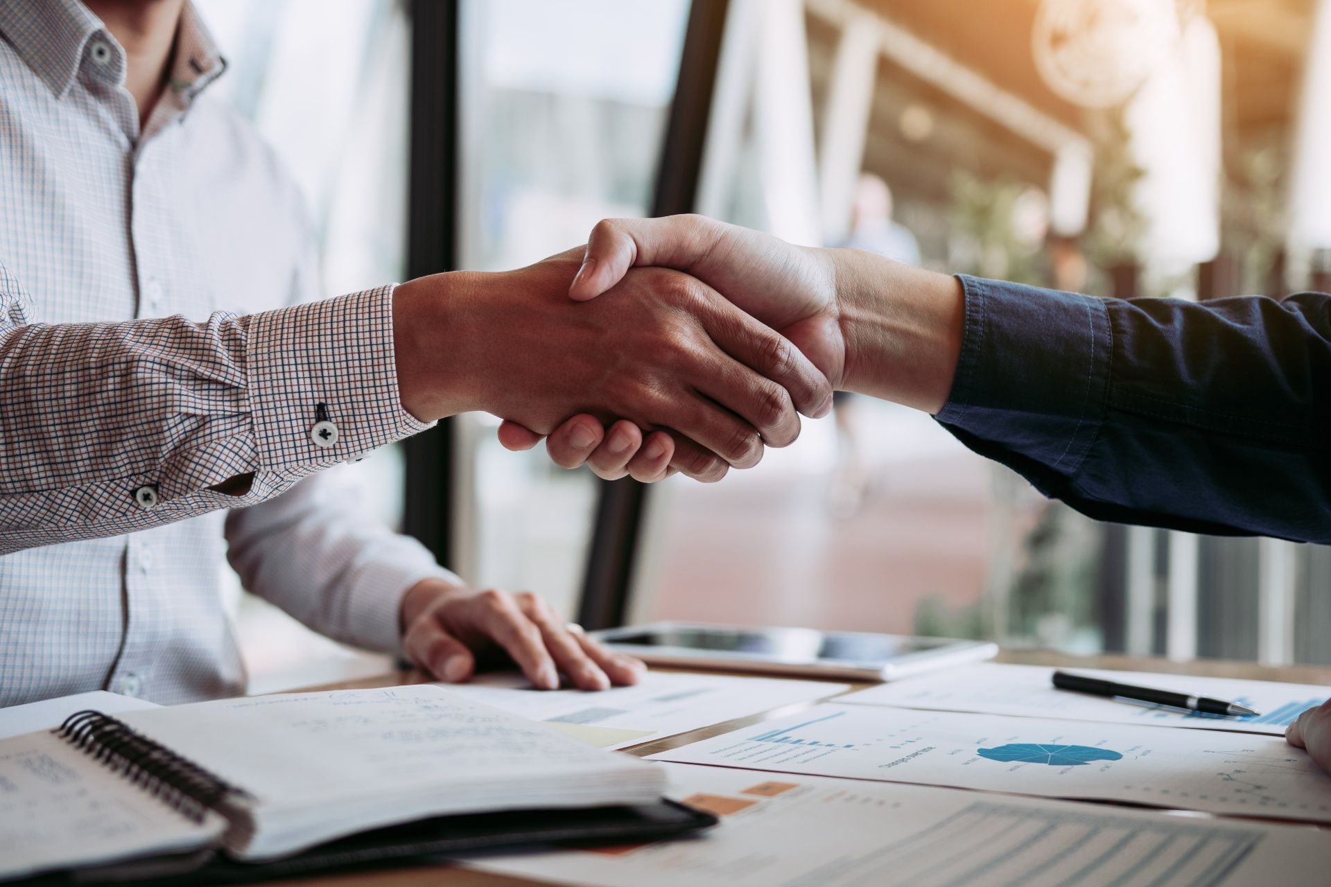Two men are shaking hands over a table.