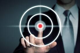 A man in a suit and tie is pointing at a target with his finger.