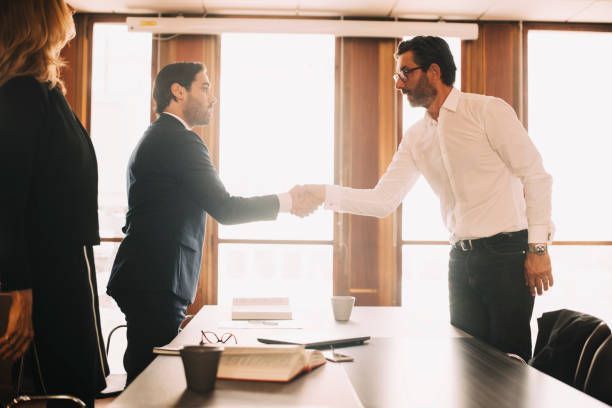 Two men are shaking hands in a conference room.