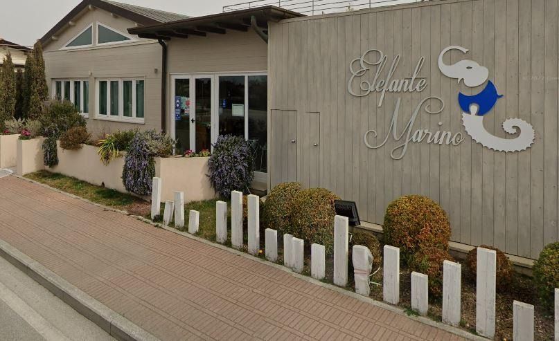 Un edificio con una parete in legno grigio su cui campeggia l'insegna 