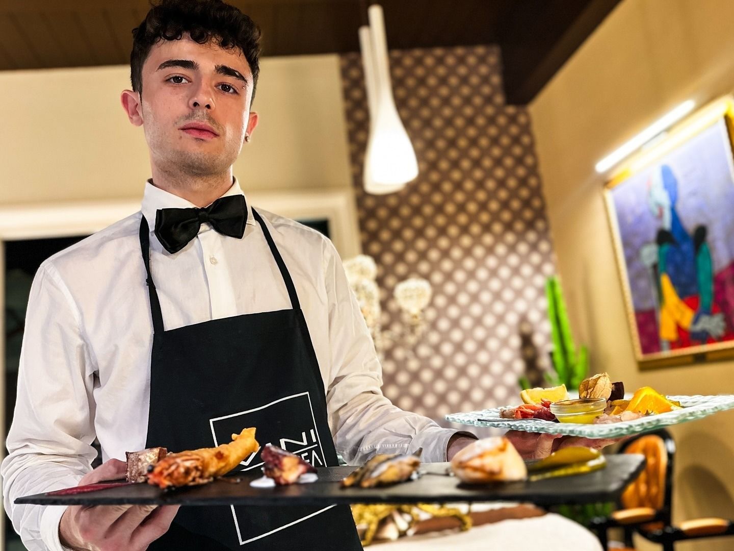 In un ristorante elegante e scarsamente illuminato, un cameriere in camicia bianca e papillon
