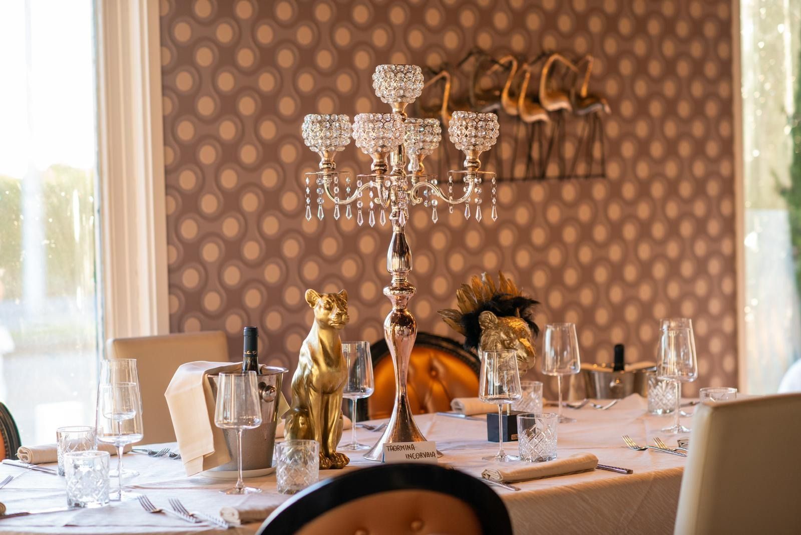 In una sala da pranzo con carta da parati a motivi decorativi, un candelabro di cristallo a cinque bracci 