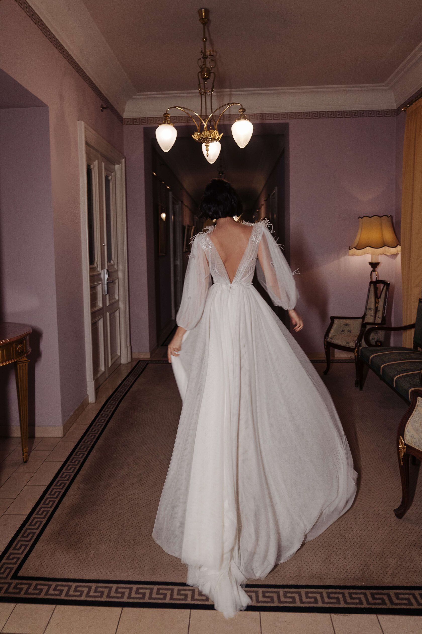 Eine Frau in einem Brautkleid steht in einem Flur.