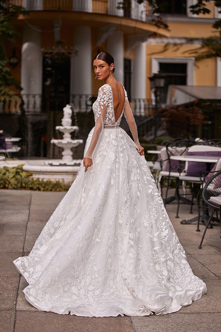 Eine Frau in einem weißen Brautkleid steht vor einem Brunnen.