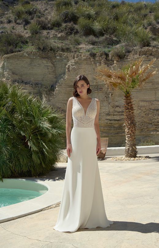 Eine Frau in einem weißen Brautkleid steht neben einem Pool.