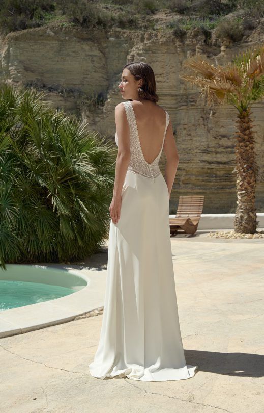 Eine Frau in einem weißen Brautkleid steht neben einem Pool.