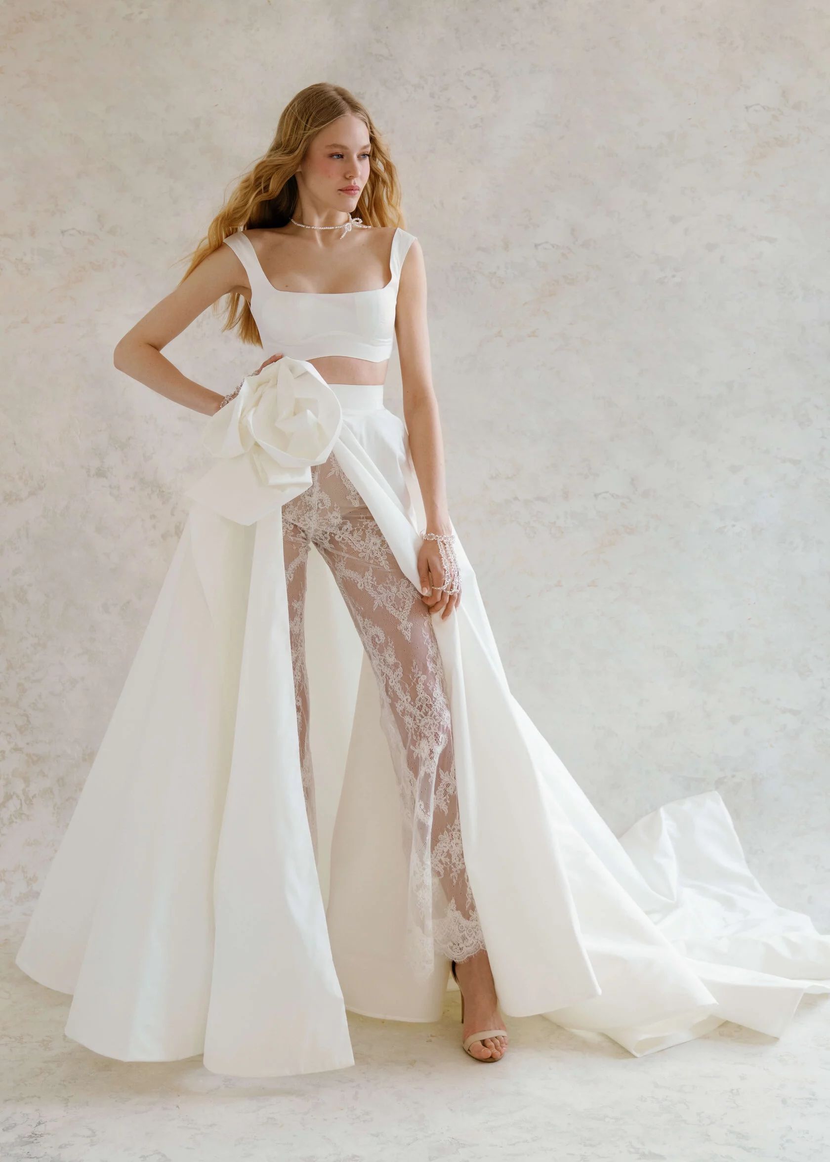 Eine Frau trägt ein weißes Brautkleid mit einer Hose darunter.