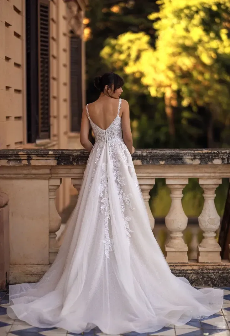 Eine Frau in einem weißen Brautkleid steht auf einem Balkon.
