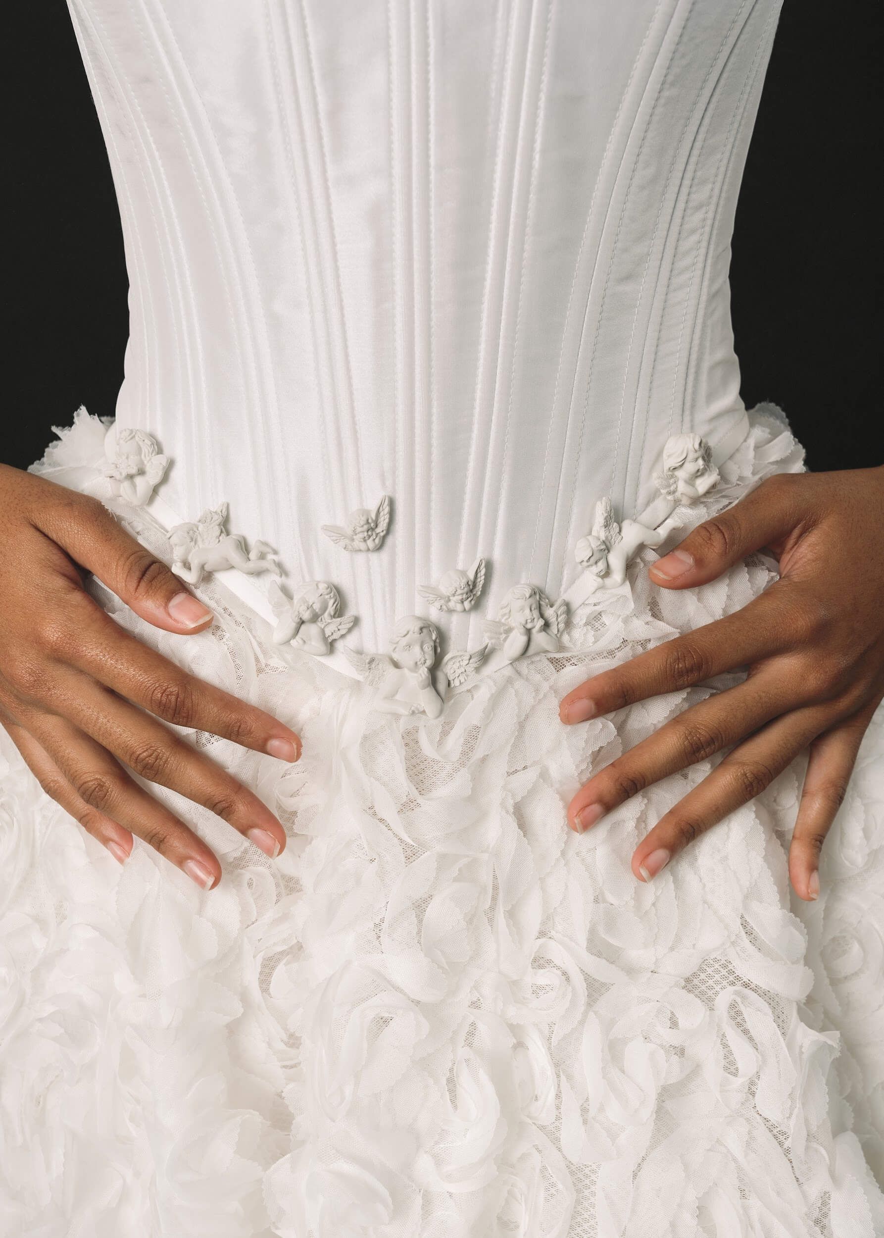Eine Frau trägt ein weißes Brautkleid und hat die Hände in die Hüften gestemmt.