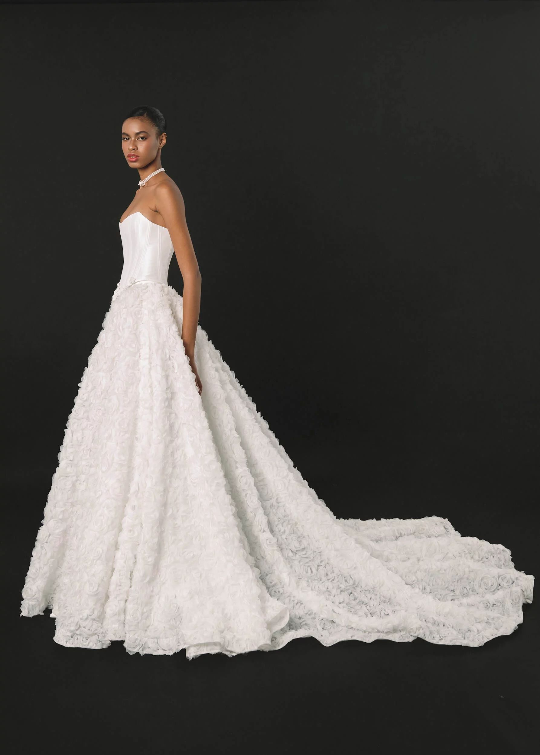 Eine Frau trägt ein weißes Brautkleid mit langer Schleppe.