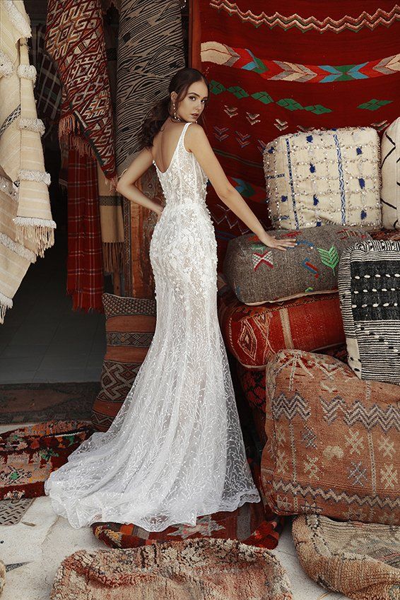 Eine Frau in einem Brautkleid steht vor einem Stapel Teppiche.