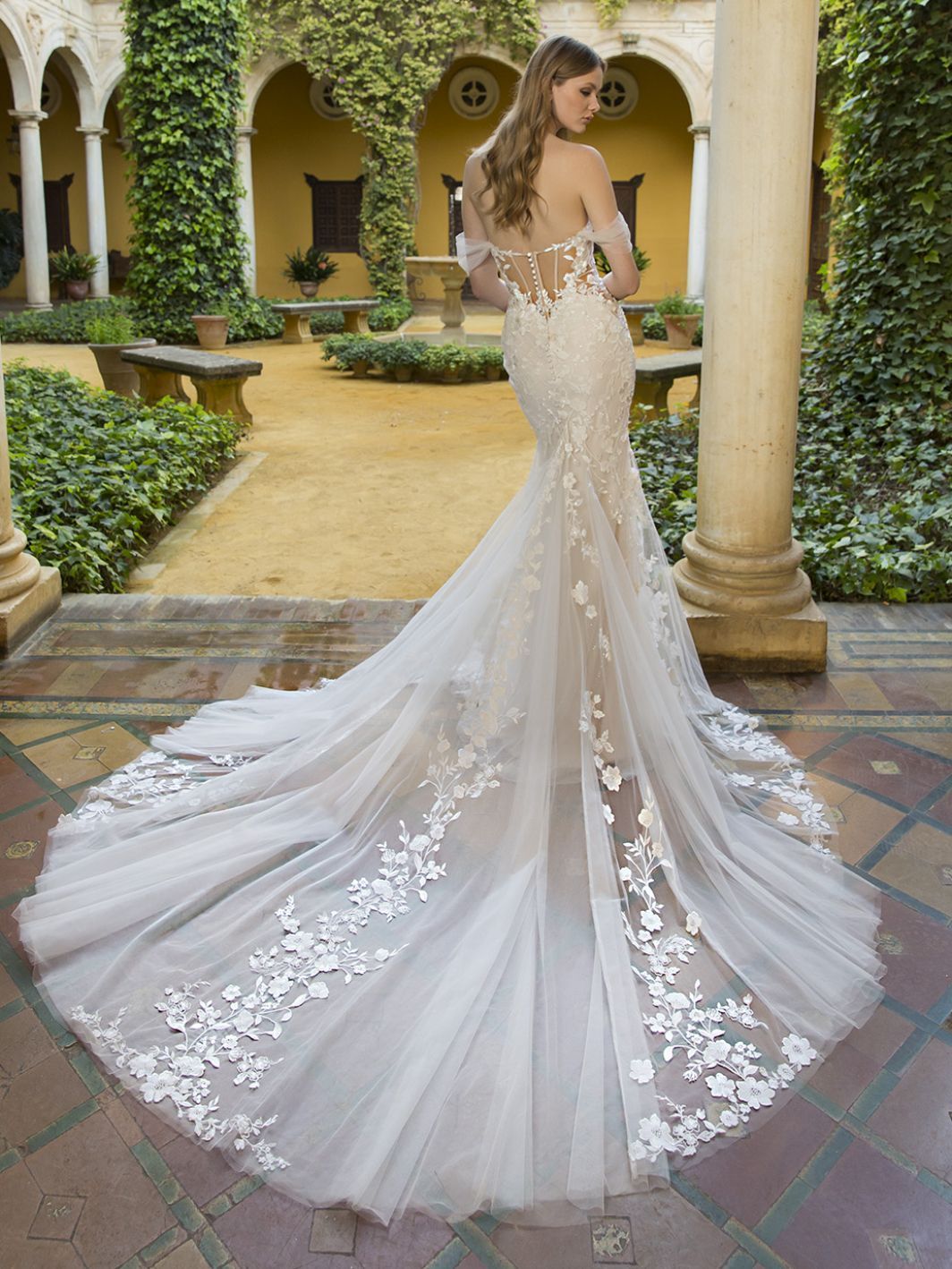 Eine Frau in einem Brautkleid steht in einem Innenhof.