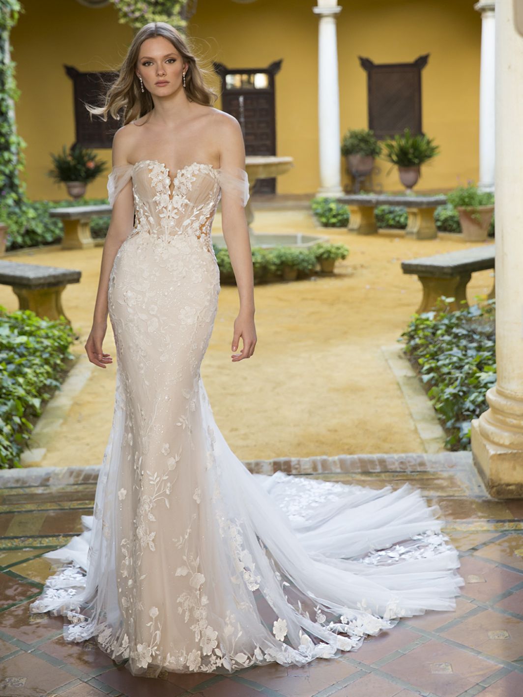 Eine Frau in einem Brautkleid steht in einem Innenhof.