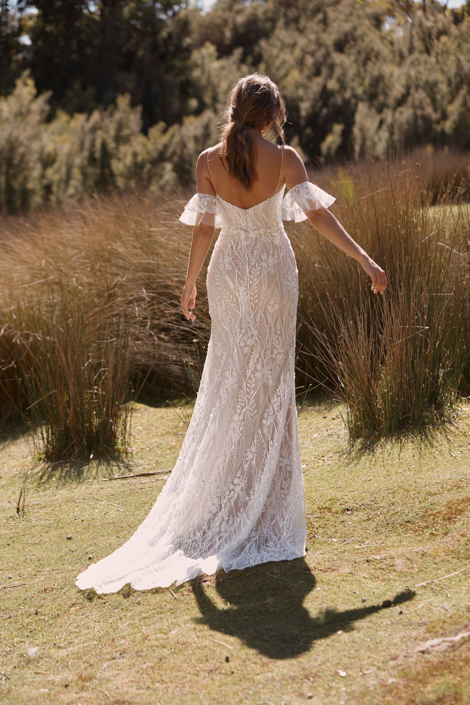 Eine Frau in einem Brautkleid steht auf einem Feld.
