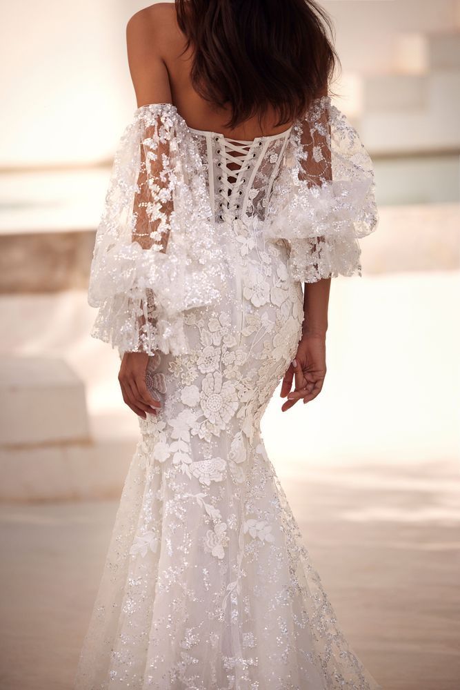 Der Rücken einer Frau, die ein weißes Brautkleid mit Rüschenärmeln trägt.