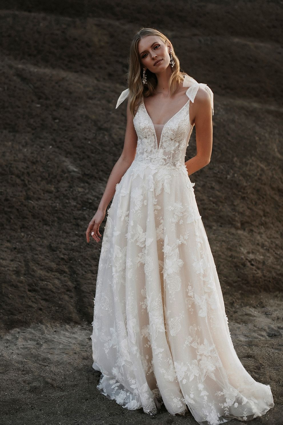 Eine Frau in einem Brautkleid steht im Dreck.