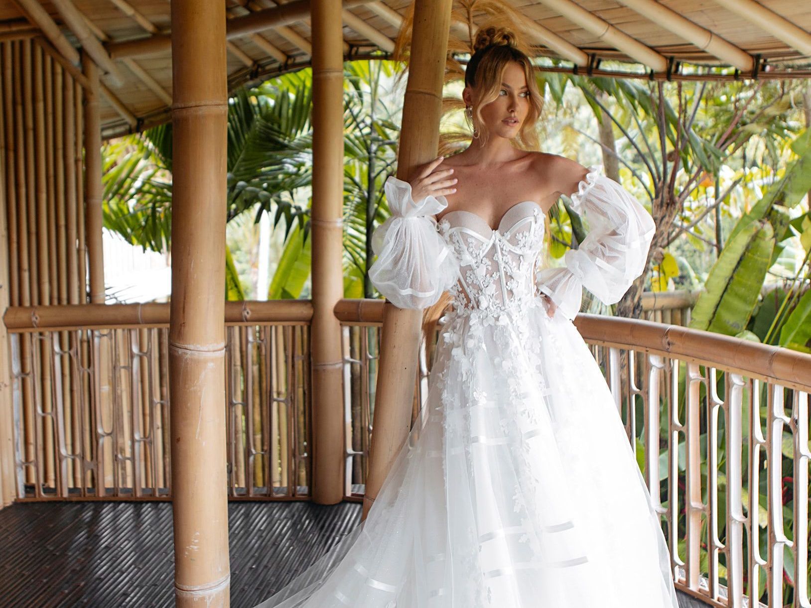 Eine Frau in einem weißen Brautkleid steht auf einem Balkon.