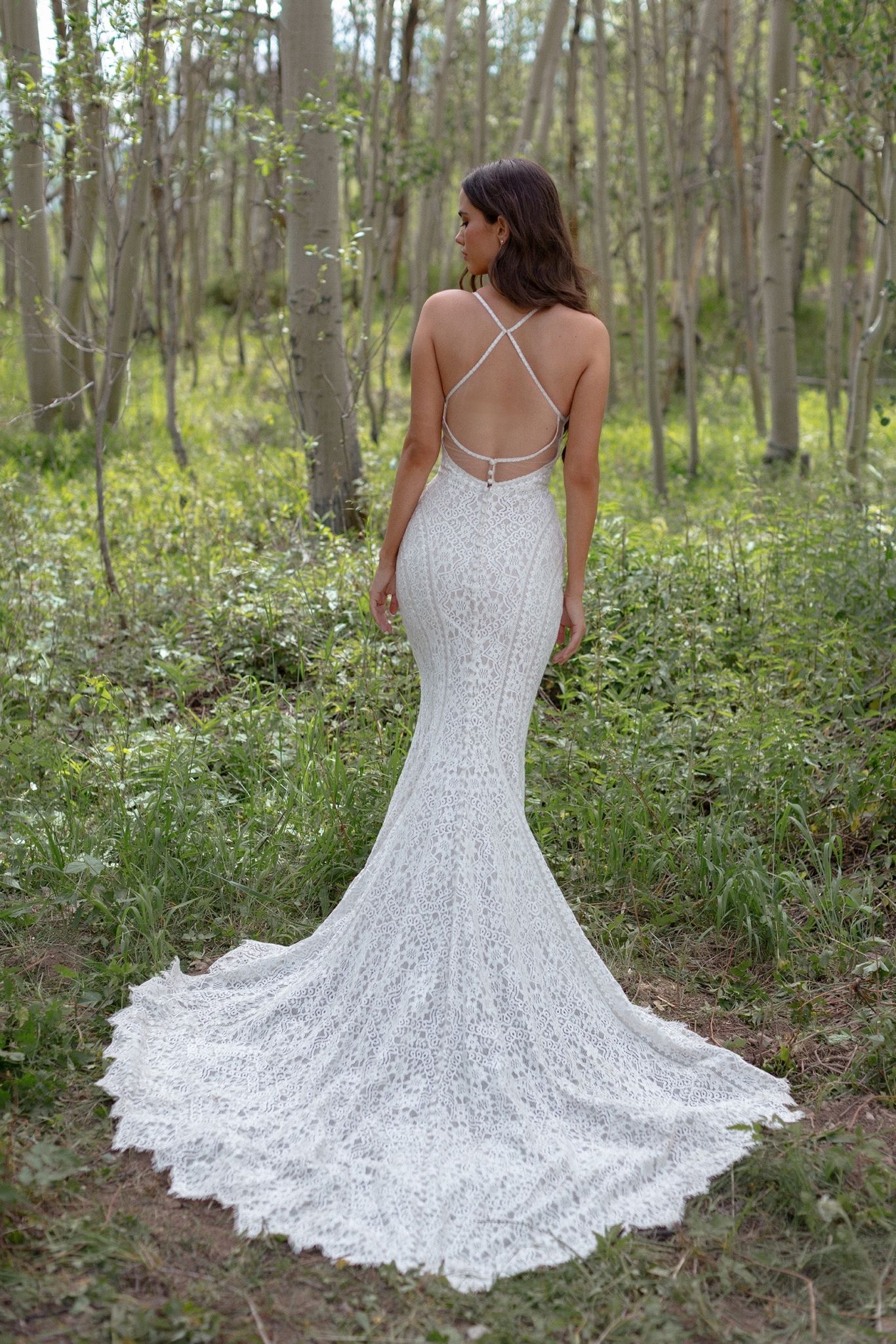 Eine Frau in einem Brautkleid steht mitten in einem Wald.