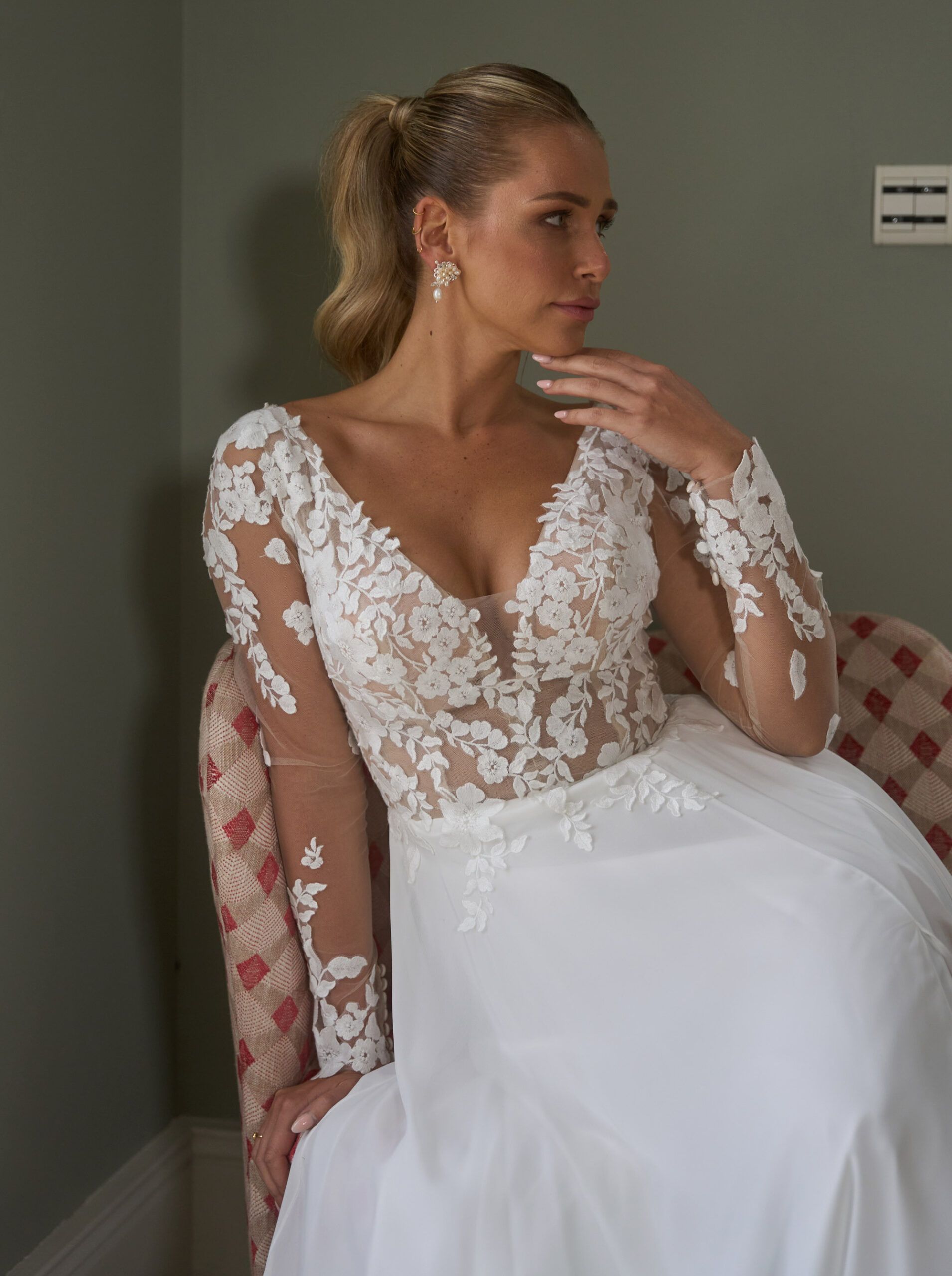 Eine Frau in einem weißen Brautkleid sitzt auf einem Stuhl.