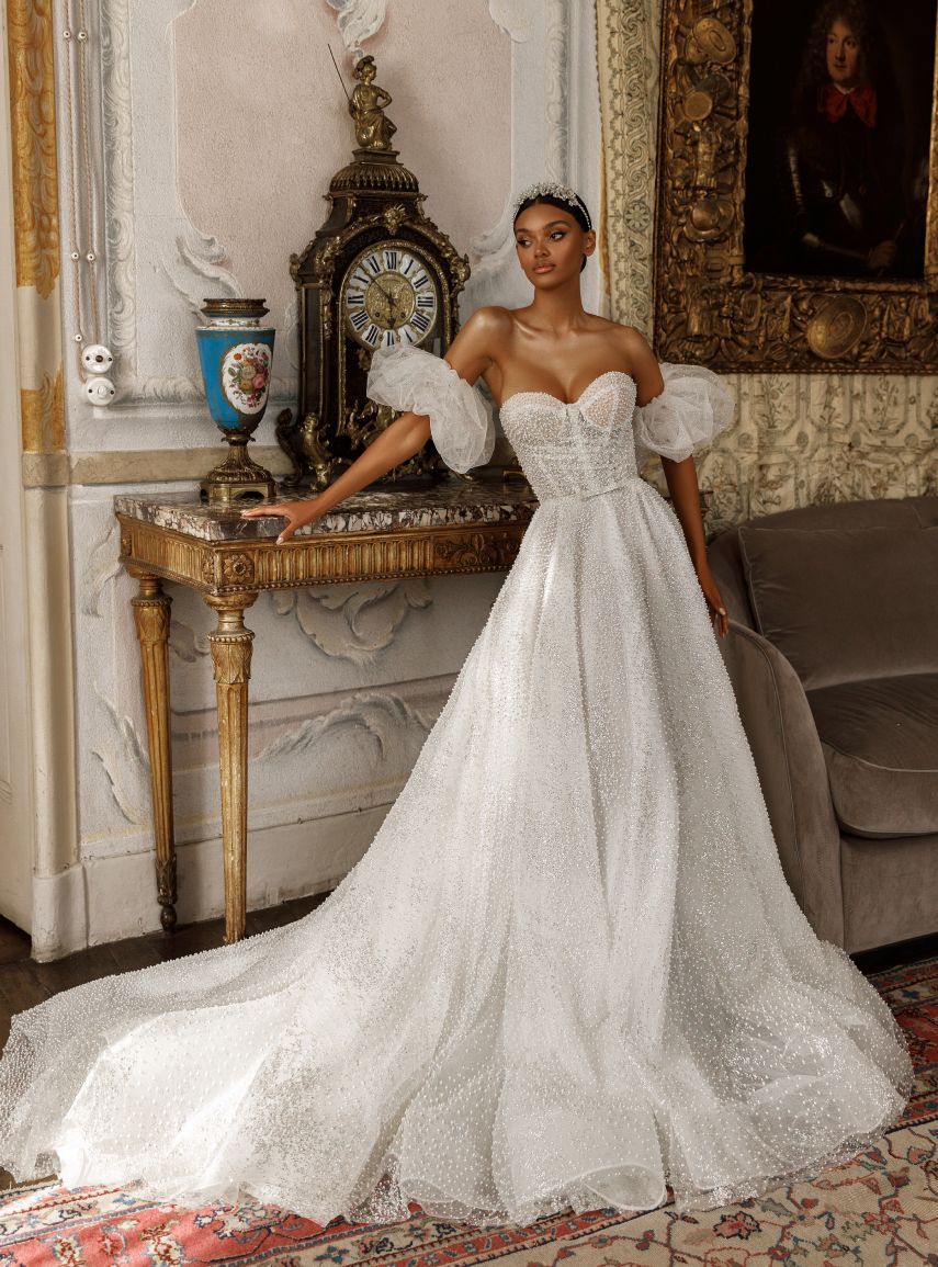Eine Frau in einem Brautkleid steht in einem Zimmer vor einer Uhr.