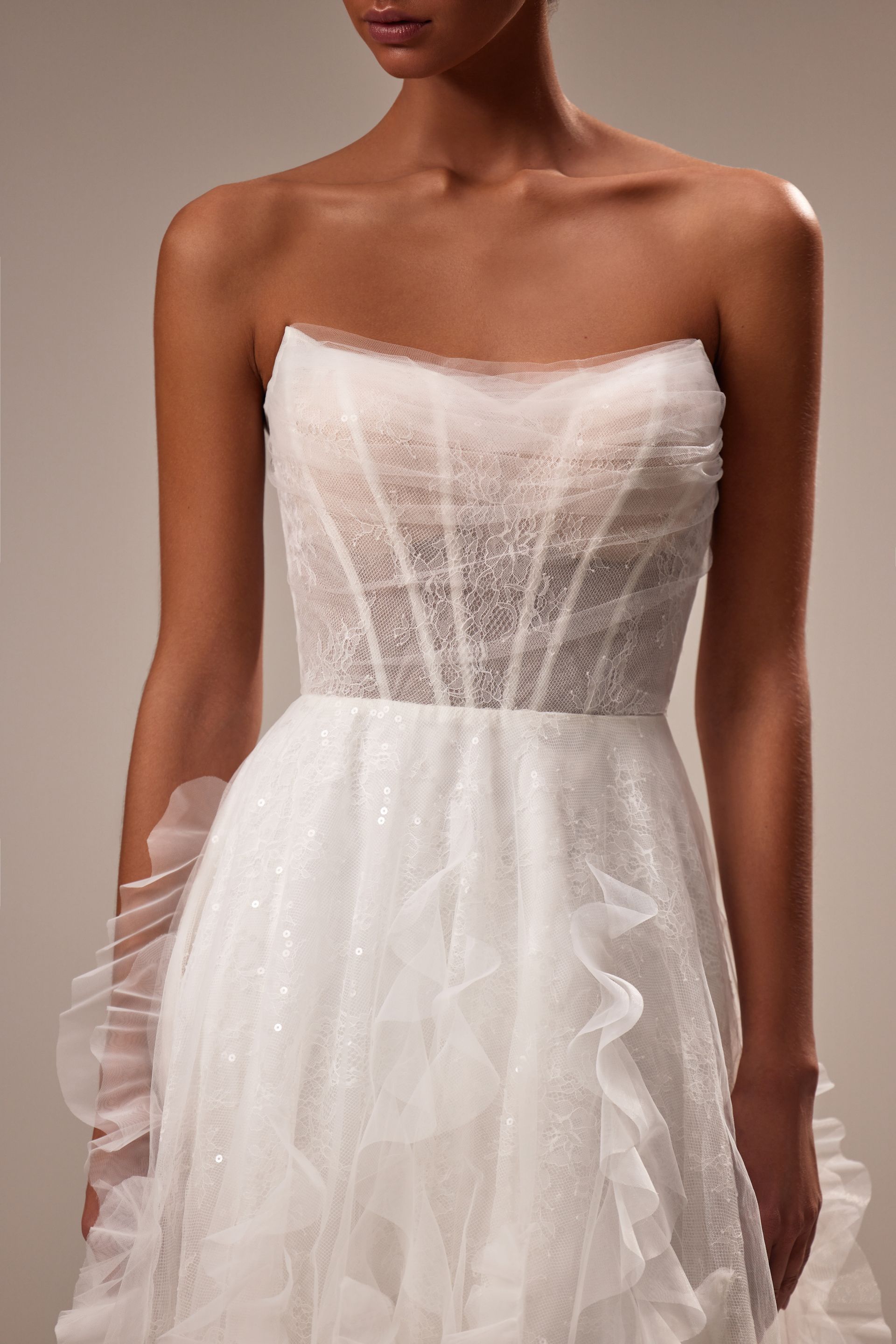 Eine Frau trägt ein weißes trägerloses Brautkleid mit Rüschen.
