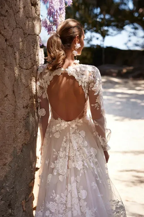 Eine Frau in einem Brautkleid steht neben einem Baum.