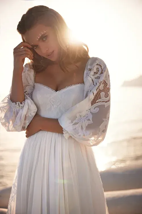 Eine Frau in einem weißen Kleid steht an einem Strand.