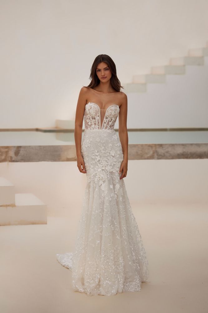 Eine Frau in einem weißen Brautkleid steht vor einer Treppe.