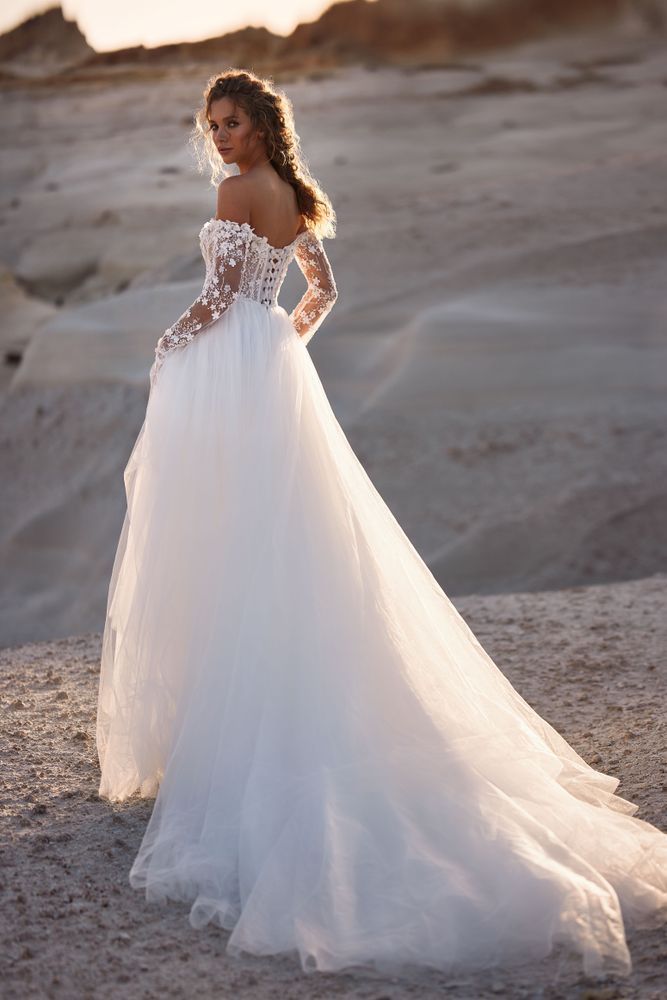 Eine Frau in einem weißen Brautkleid steht in der Wüste.